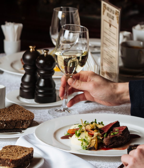 고급 레스토랑에서 와인을 따르는 모습과 정갈하게 플레이팅된 고급 요리가 있는 식사 장면